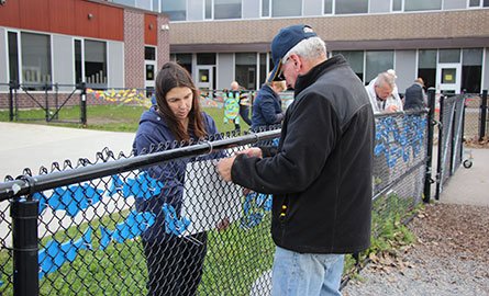 Stream of Dreams volunteers install fish along fence